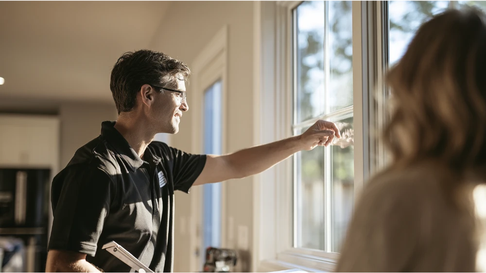 Homeowner discussing window seal failure and replacement options with a professional window installer